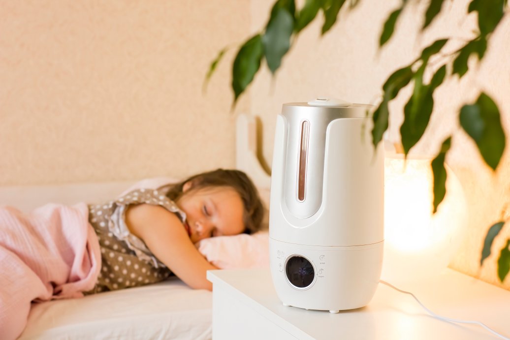 Cute little girl sleeping in bedroom with air humidifier