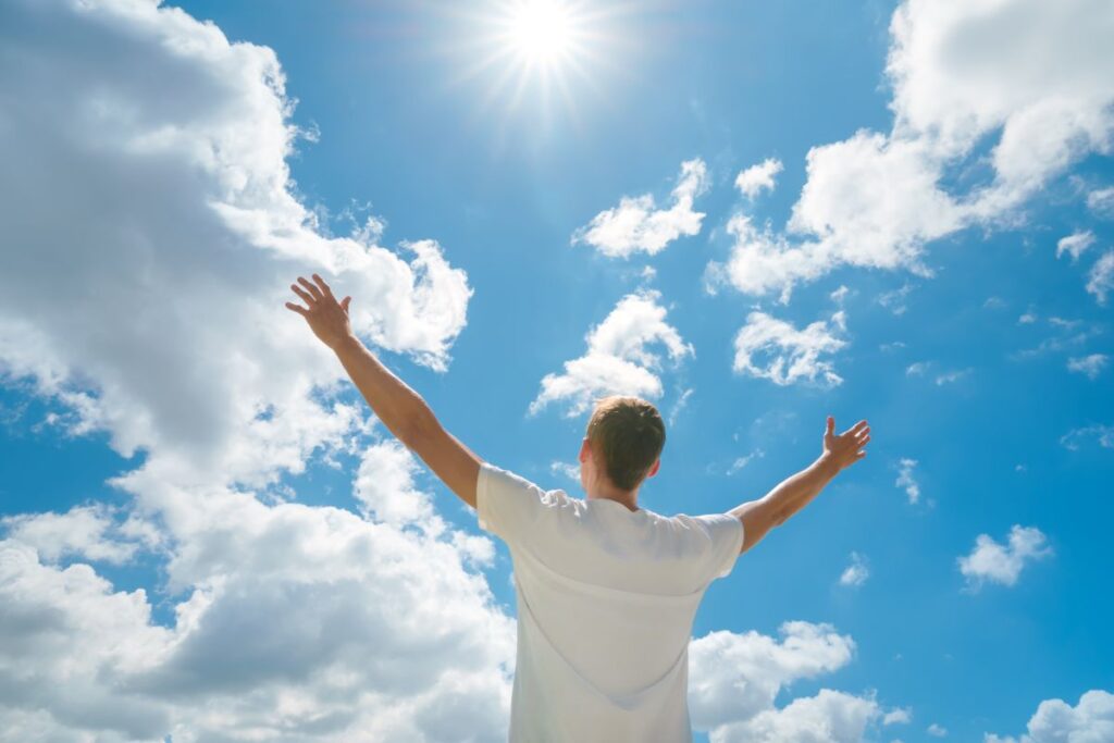 Man hands up to the deep blue sky and sun